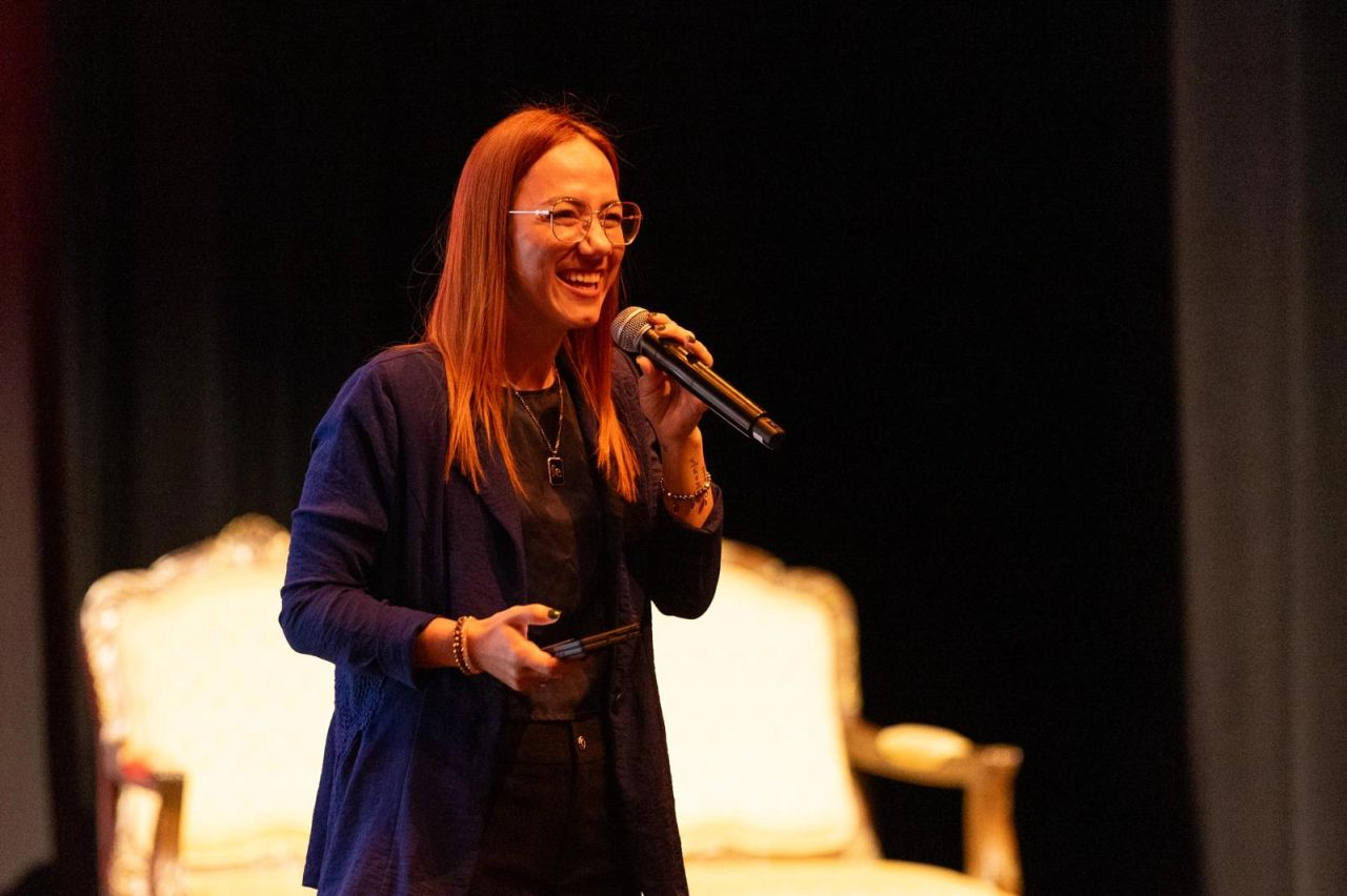 Dra. Mariluz Serrano Ortiz sonriendo durante una conferencia, con un micrófono en la mano.